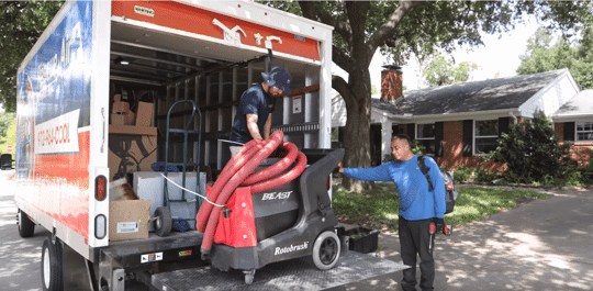 Tech lowering air duct cleaning equipment from a company truck