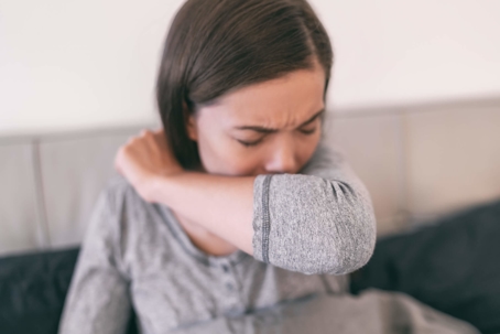 woman coughing into arm